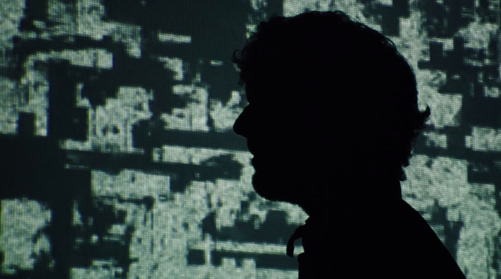 a silhouette of a man in front of a large screen