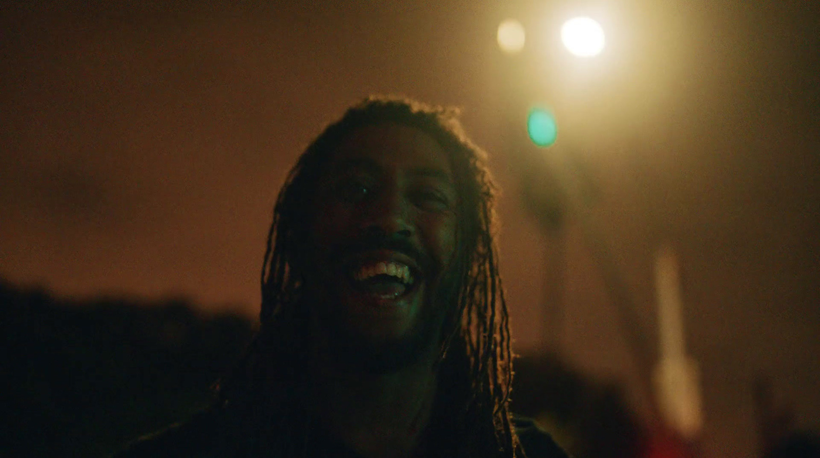 a man laughing in the dark with a street light in the background