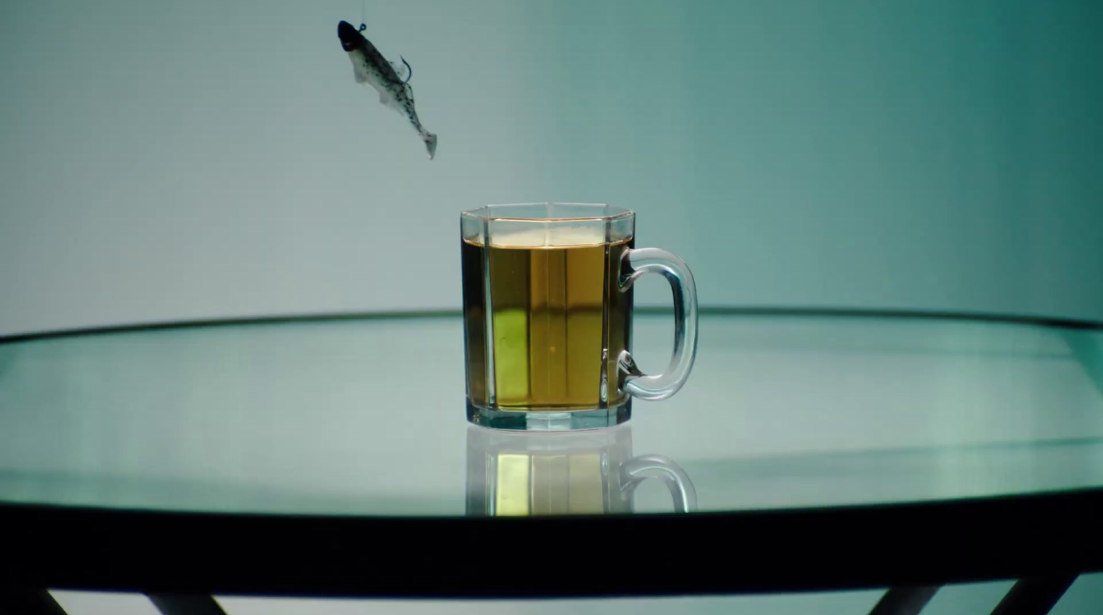 a fish is flying over a glass of tea