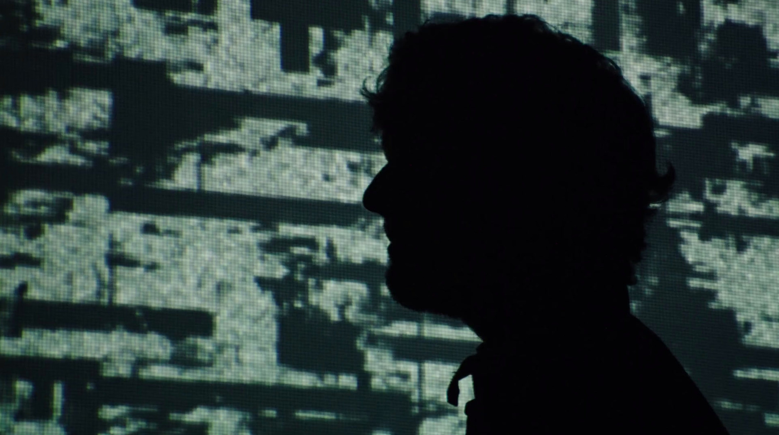 a silhouette of a man in front of a large screen