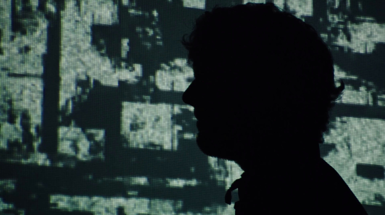 a silhouette of a man in front of a large screen