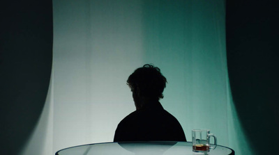 a person sitting at a table with a glass in front of them