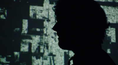 a silhouette of a man in front of a large screen