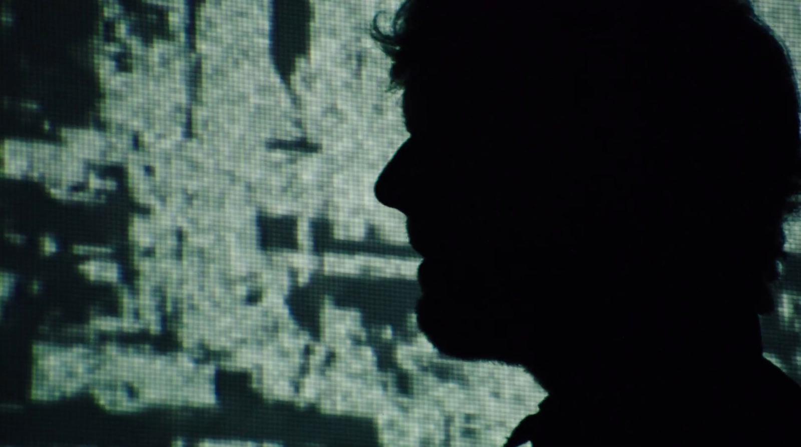 a silhouette of a man in front of a large screen