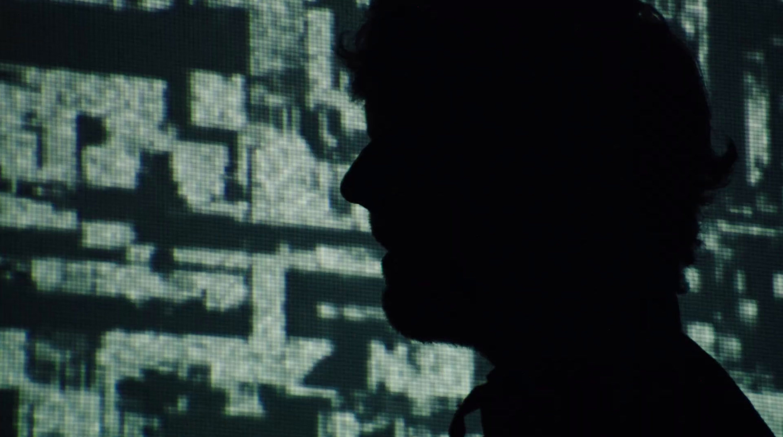 a silhouette of a man in front of a screen