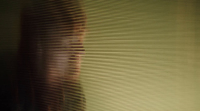 a blurry photo of a woman's face behind blinds