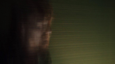 a man's face is seen through the blinds of a window