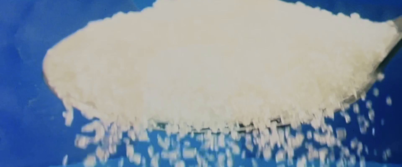 a large amount of sugar being poured into a blue bowl