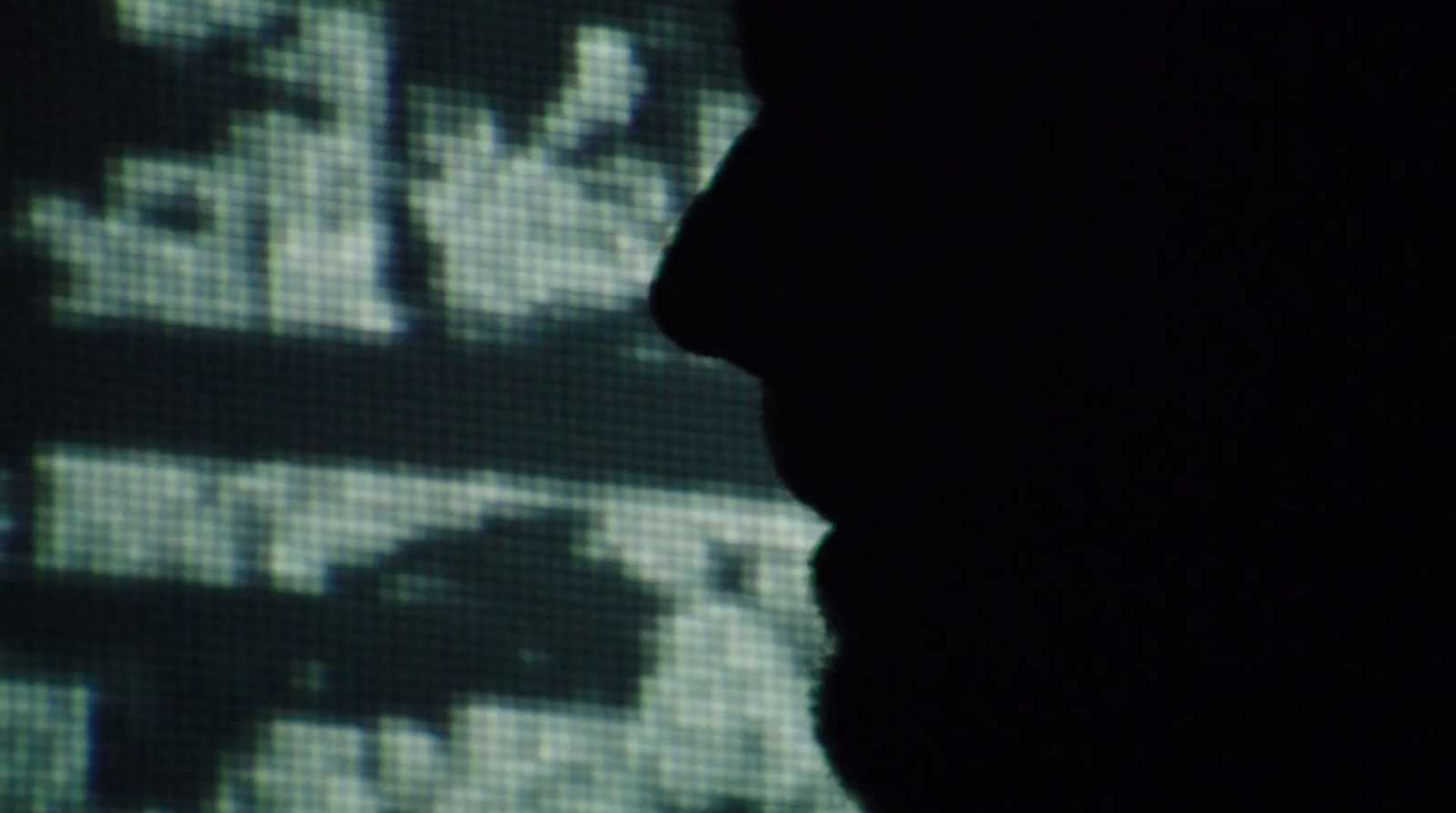 a silhouette of a man in front of a computer screen