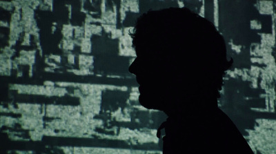 a silhouette of a man in front of a large screen