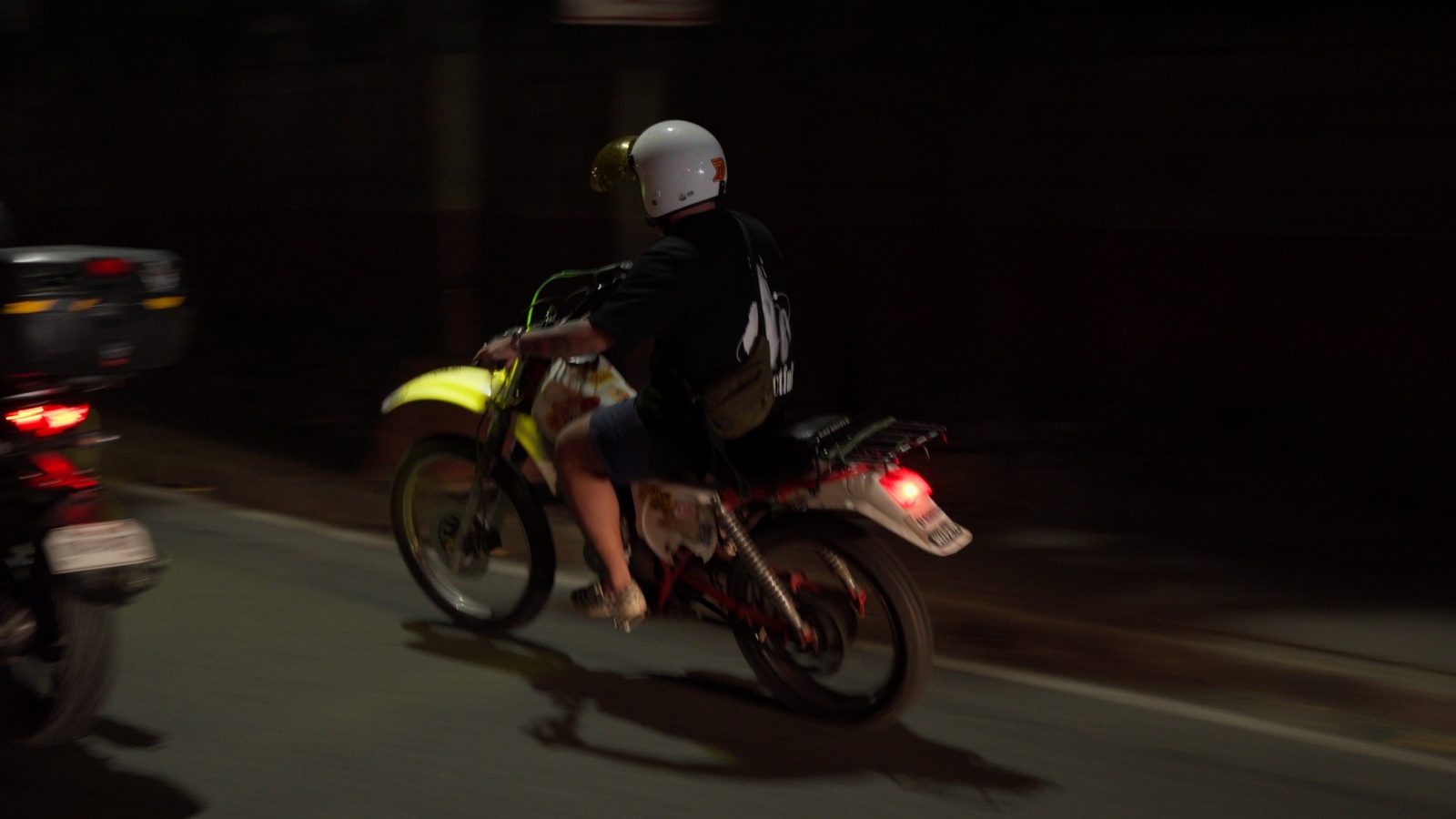 a man riding a motorcycle down a street at night