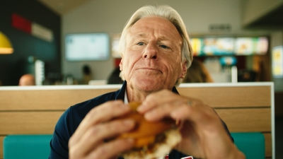 a man sitting at a table eating a sandwich