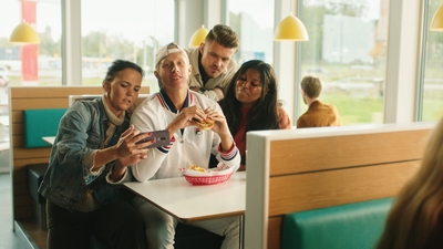 a group of people sitting around a table looking at a cell phone