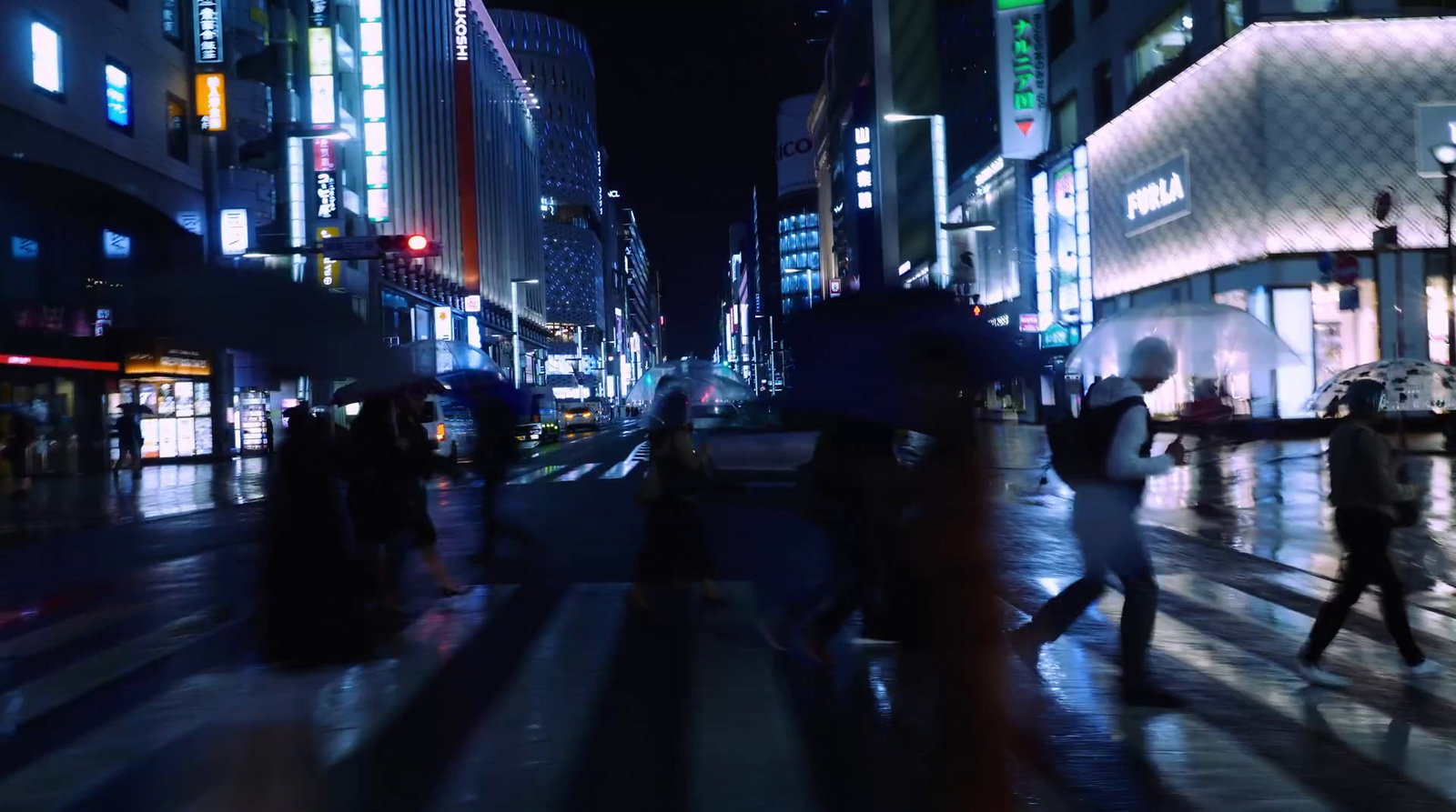 a group of people walking across a street at night