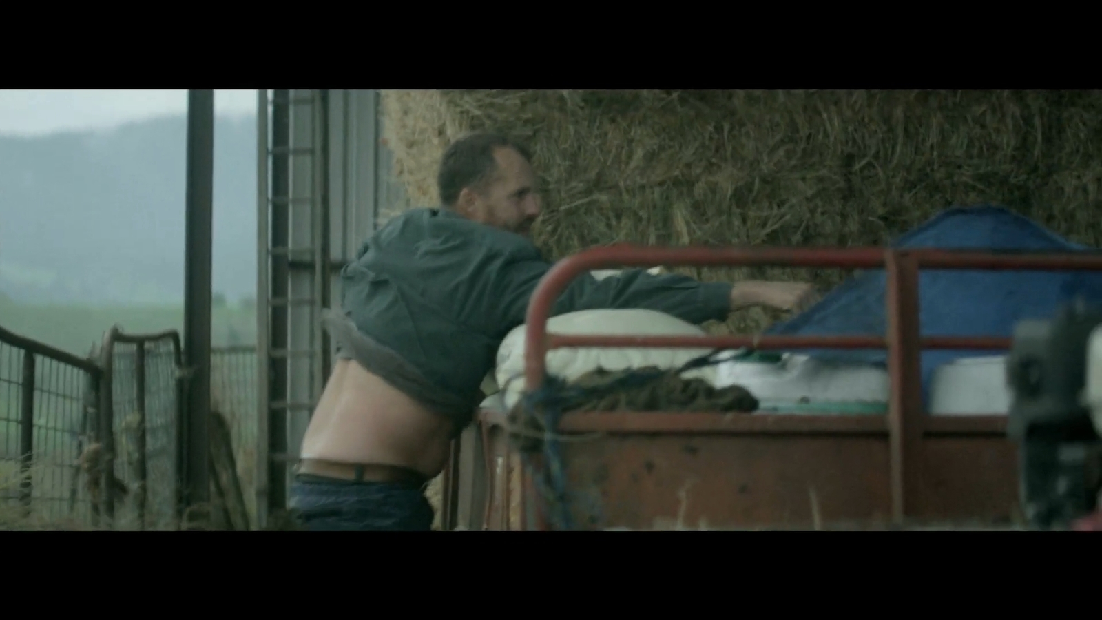 a man standing next to a pile of hay