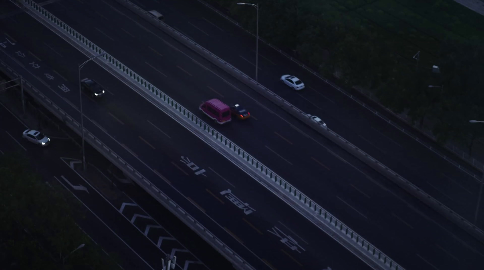 a red car driving down a highway next to tall buildings