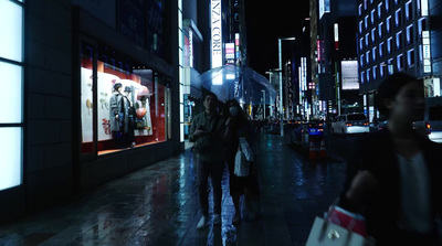 a couple of people walking down a street at night