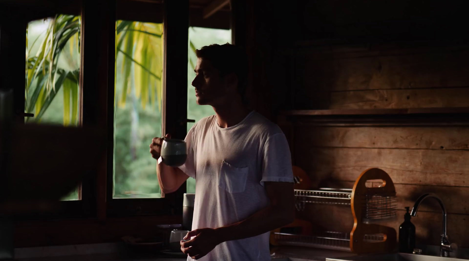 a man standing in a kitchen next to a window