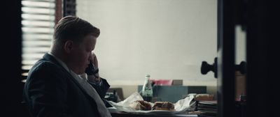 a man sitting at a desk talking on a cell phone