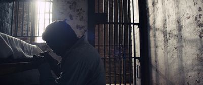 a man sitting in a jail cell holding a cell phone