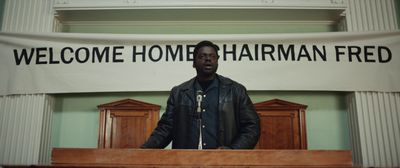 a man standing at a podium in front of a welcome home sign