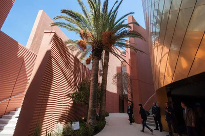 a group of people walking down a sidewalk next to a building