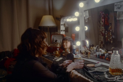 a woman sitting in front of a mirror in a dressing room