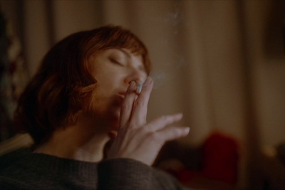 a woman smoking a cigarette in a dark room