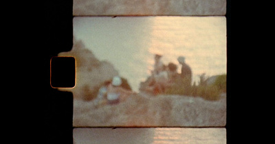 a group of people sitting on a beach next to a body of water