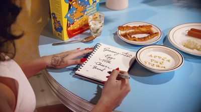 a woman sitting at a table writing on a notebook