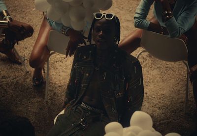 a man sitting in a chair surrounded by balloons