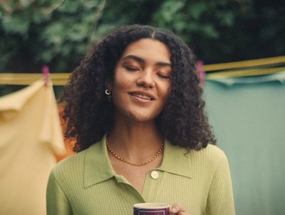 a woman with curly hair holding a cup of coffee