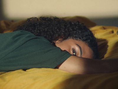 a woman laying on a bed with a green shirt