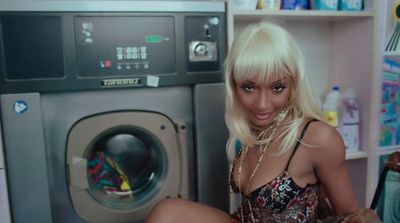 a blonde woman sitting next to a washing machine