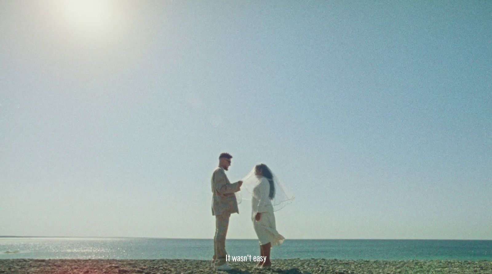 a man and woman standing on a beach next to the ocean