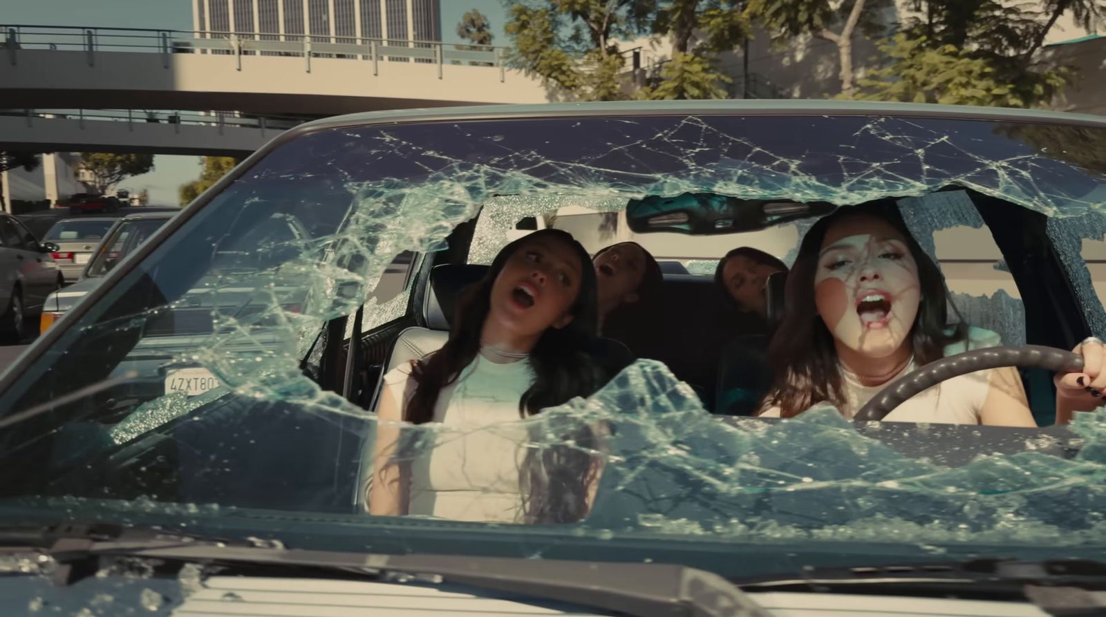 a group of people sitting in a car with a broken windshield