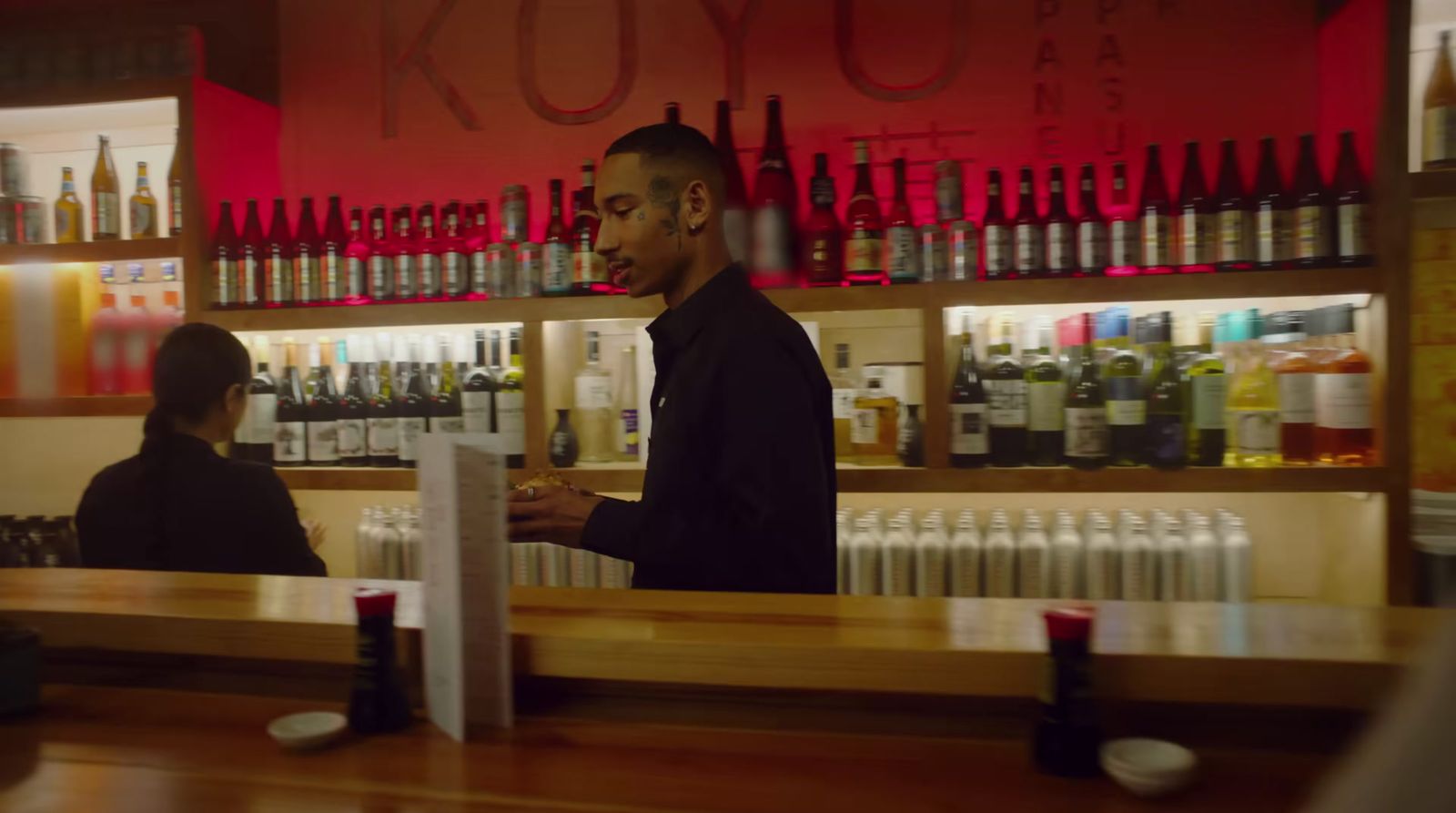 a man standing in front of a bar next to a woman