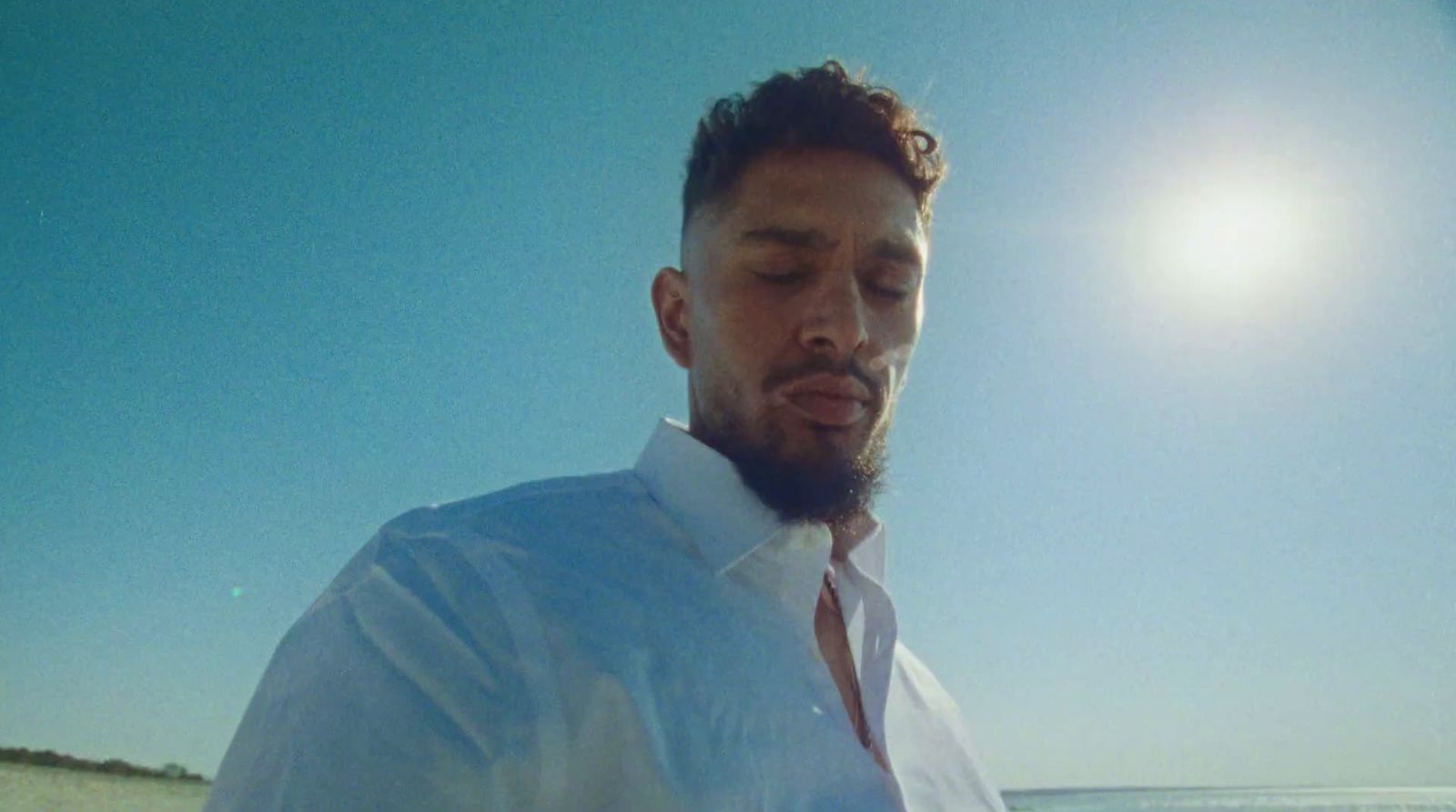 a man in a white shirt and tie on the beach