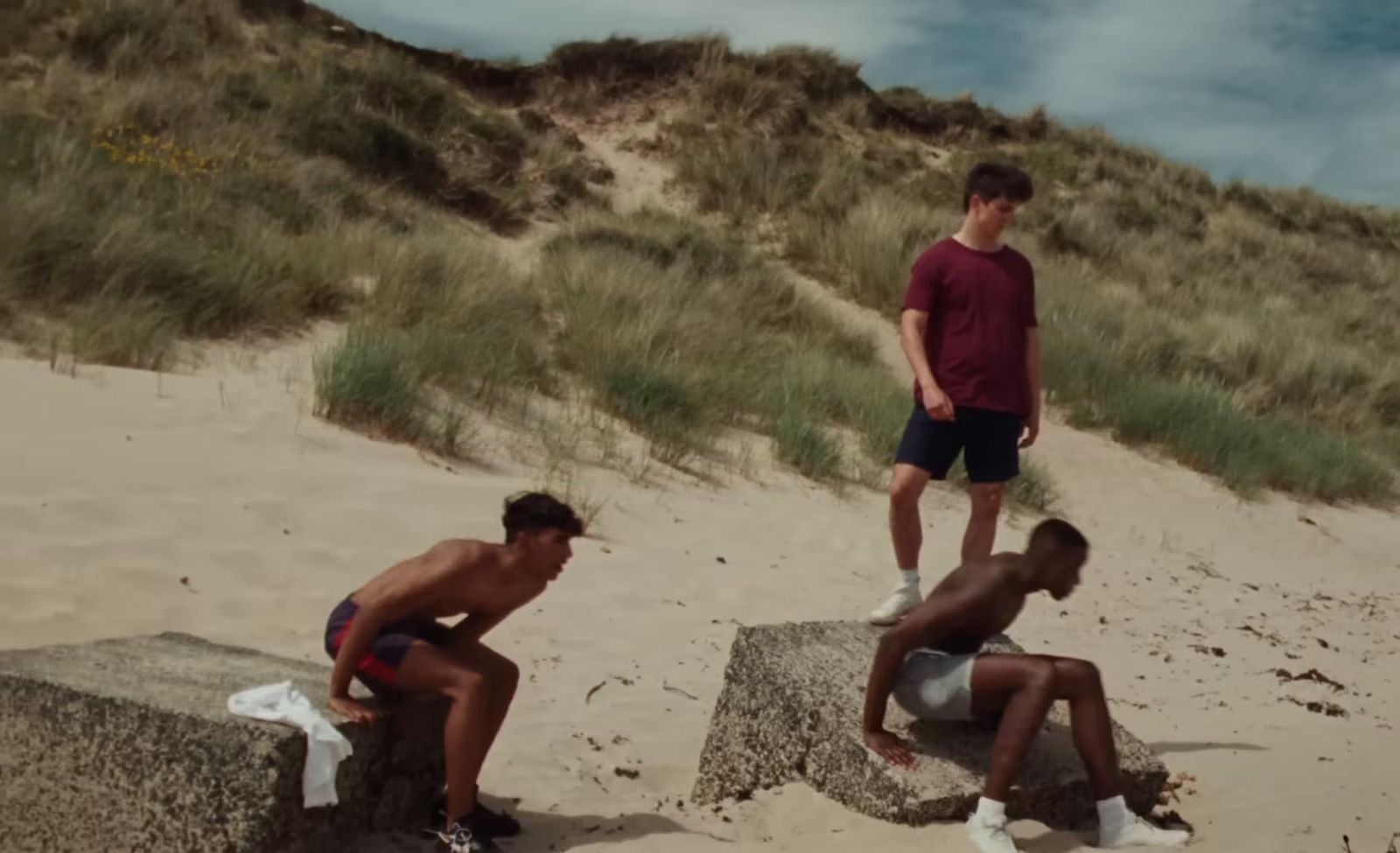 three men are sitting on a rock on the beach