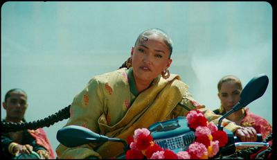 a woman sitting on a motorcycle with other people behind her