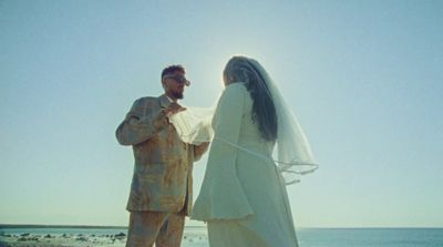 a man and a woman standing on a beach next to the ocean