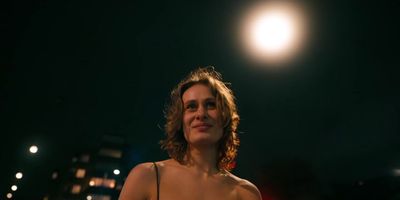 a woman standing in front of a street light at night