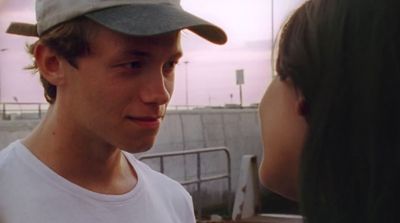 a man in a baseball cap talking to a woman