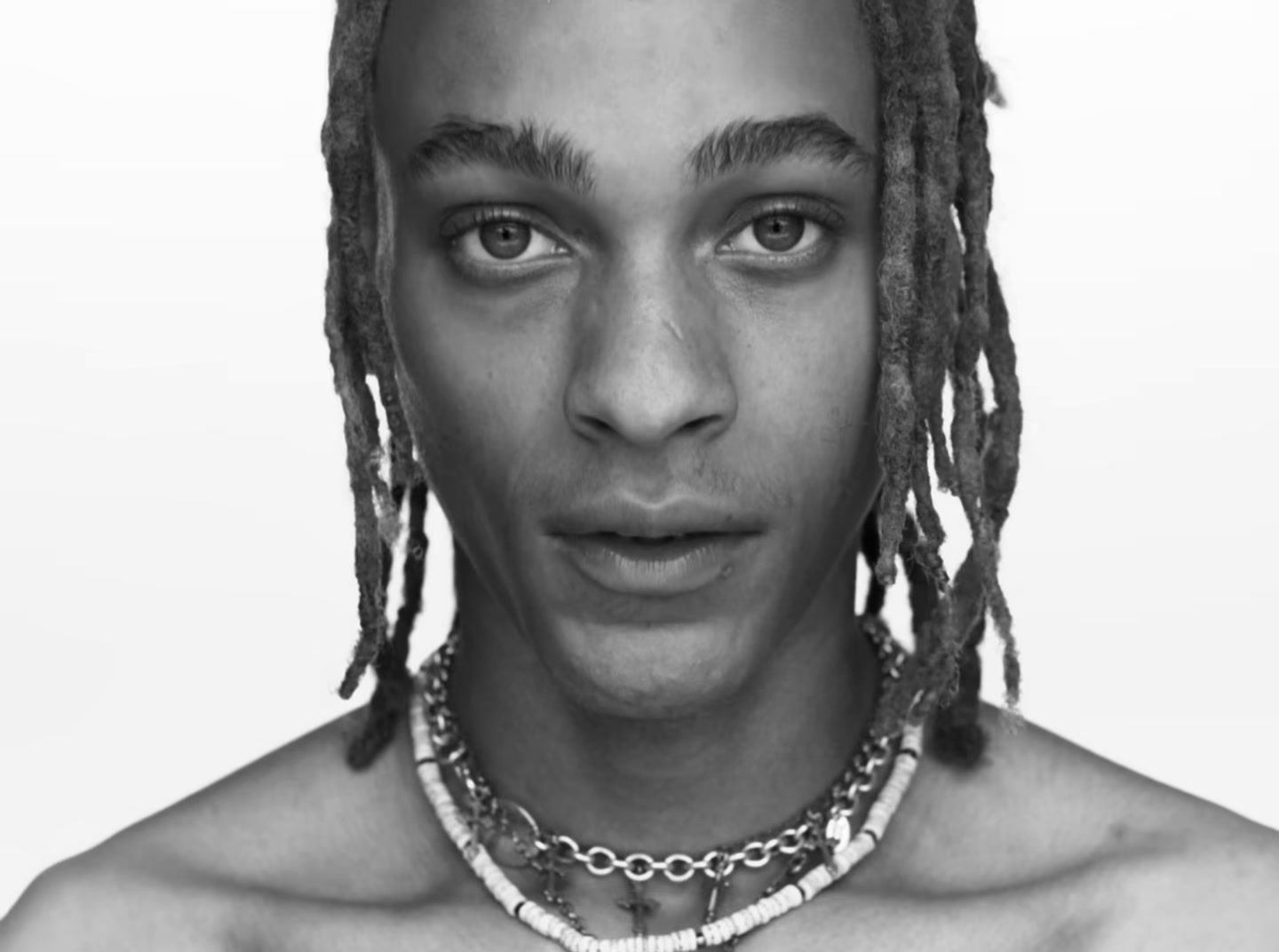 a man with dreadlocks and a necklace on his neck