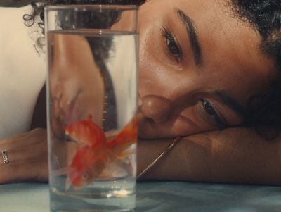 a woman looking at a goldfish in a glass of water