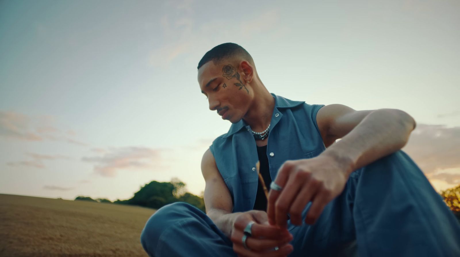 a man sitting in a field with a cigarette in his hand