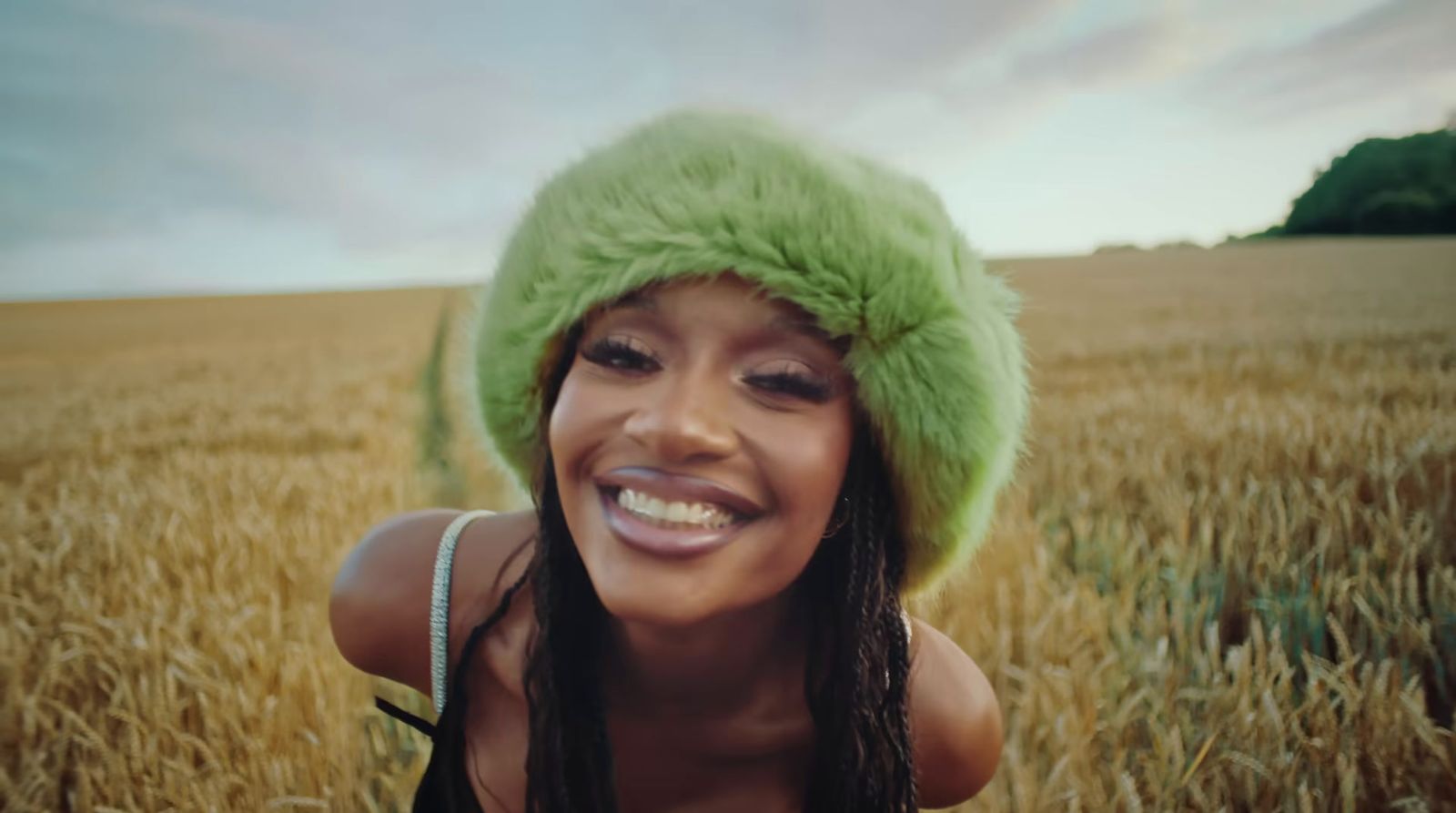 a woman wearing a green hat in a wheat field