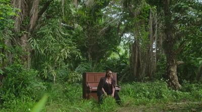 a woman sitting on a bench in the middle of a forest