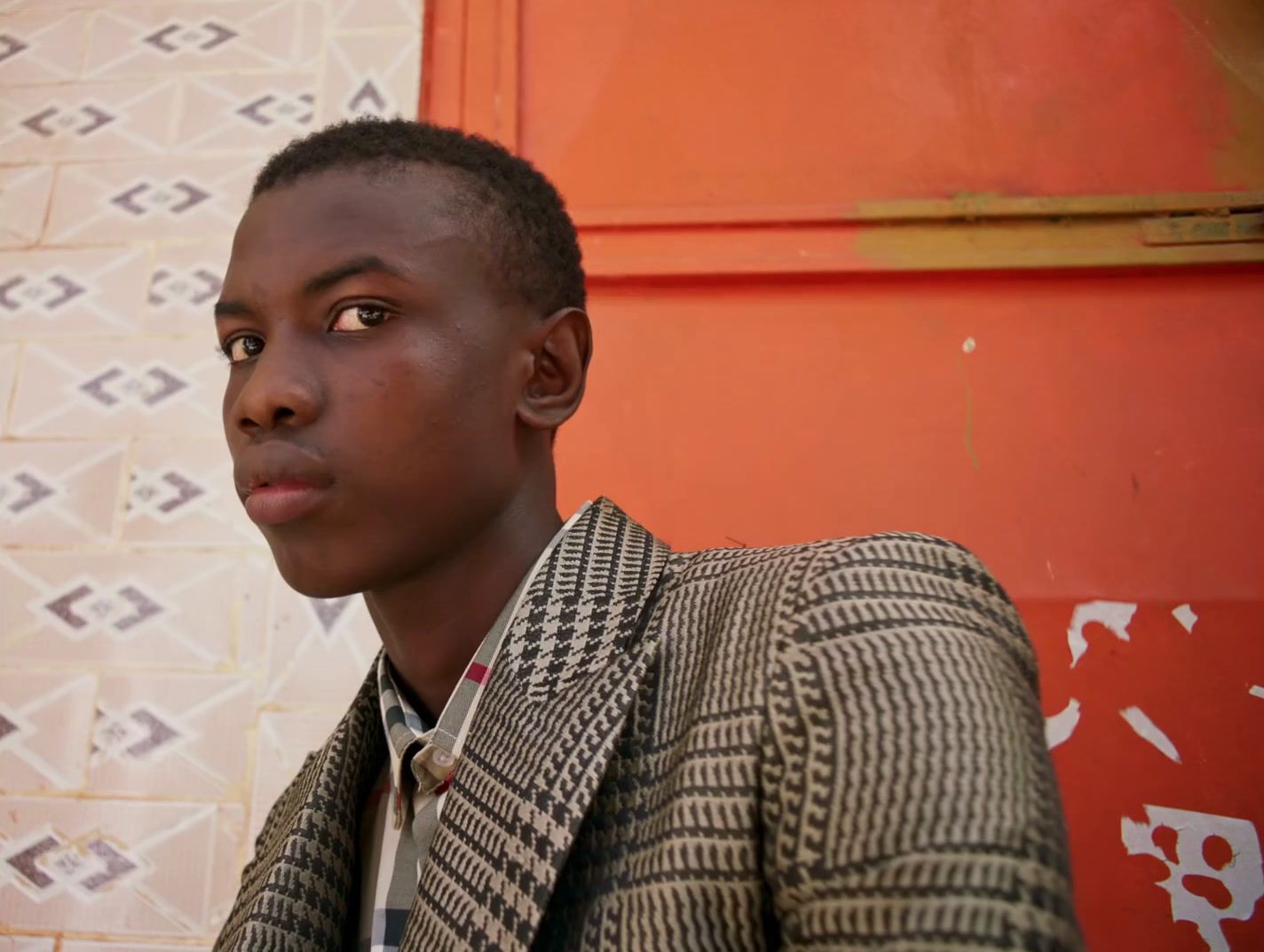 a young man standing in front of a wall