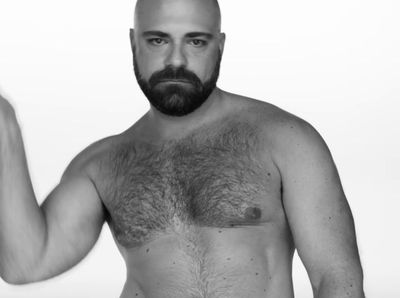 a man with a beard and no shirt holding a cell phone